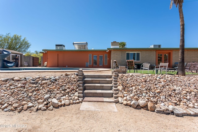 ranch-style home with french doors, a swimming pool, a patio, and a chimney