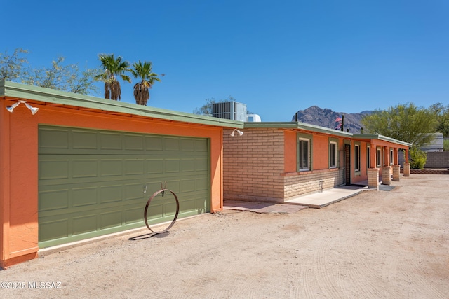 view of front of home with brick siding, central AC, a mountain view, and a garage
