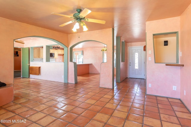 interior space with light tile patterned floors, arched walkways, and a ceiling fan