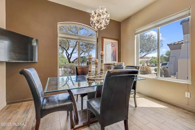 dining area with baseboards, wood finished floors, and a chandelier