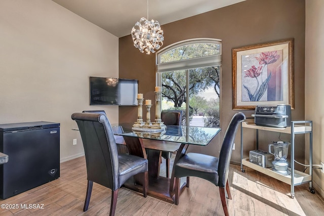dining area featuring baseboards, wood finished floors, and a notable chandelier