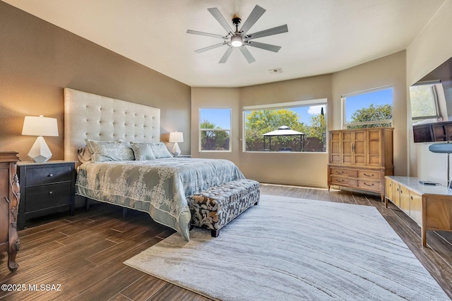 bedroom featuring a ceiling fan, dark wood finished floors, multiple windows, and visible vents