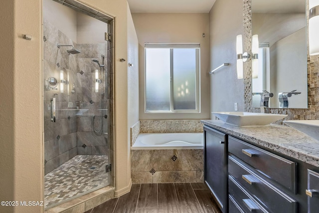 bathroom with a sink, double vanity, wood finished floors, a bath, and a stall shower
