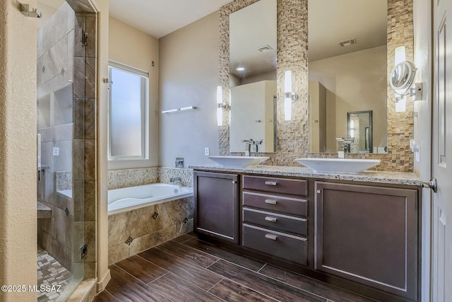 bathroom featuring visible vents, a sink, a garden tub, and a stall shower