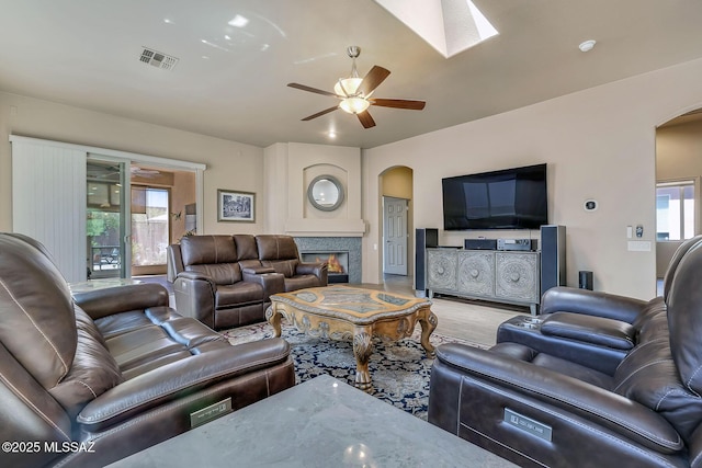 living room with visible vents, arched walkways, a ceiling fan, and a wealth of natural light