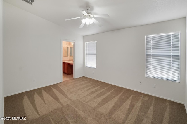 unfurnished bedroom with light colored carpet, baseboards, ensuite bath, and visible vents