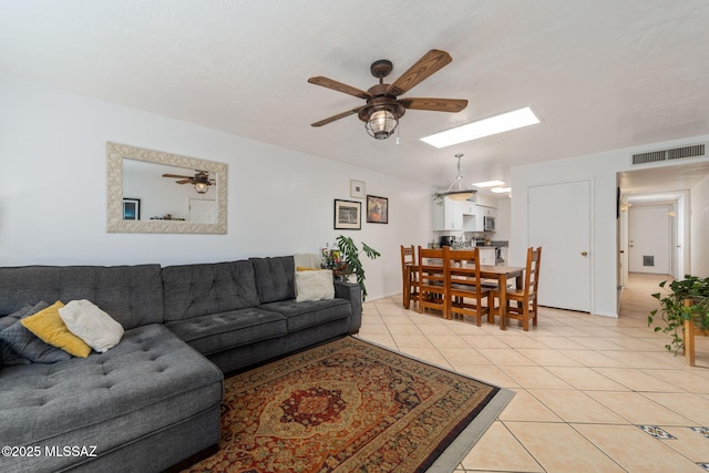 living room with light tile patterned flooring, ceiling fan, visible vents, and a skylight