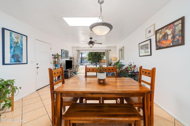 dining room featuring a ceiling fan, light tile patterned flooring, and a skylight