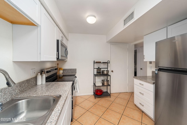kitchen featuring a sink, stainless steel appliances, white cabinetry, light tile patterned floors, and visible vents