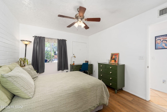 bedroom featuring baseboards, ceiling fan, wood finished floors, and visible vents
