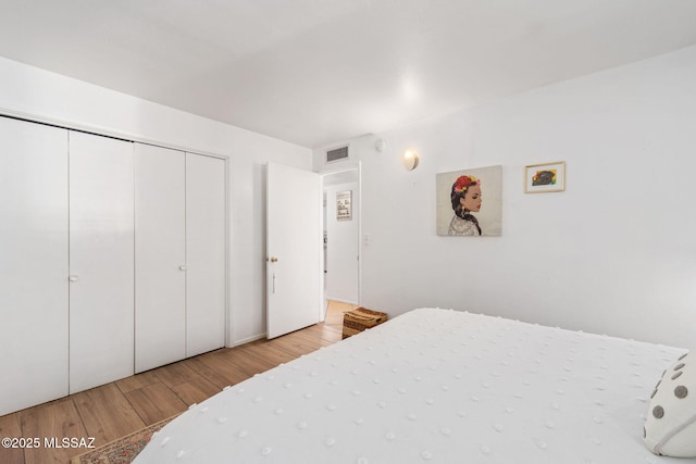 bedroom featuring visible vents, wood finished floors, and a closet