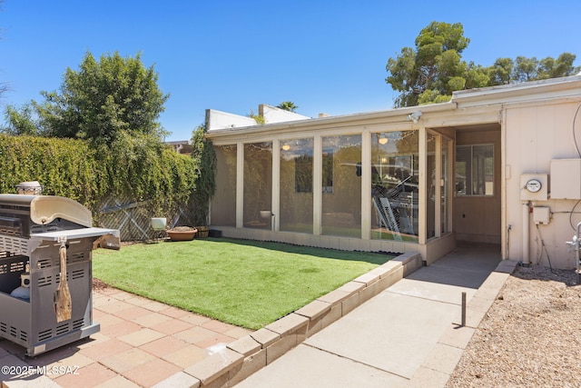 back of house featuring fence, a yard, a patio, and a sunroom