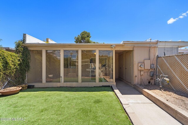 back of property with fence and a lawn