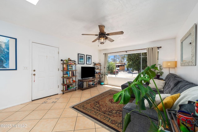 living area featuring a ceiling fan, baseboards, and light tile patterned floors