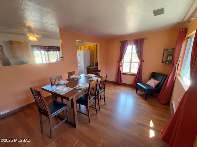 dining space featuring baseboards, visible vents, wood finished floors, and a textured ceiling