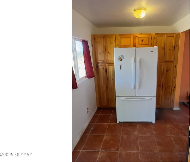 kitchen with baseboards, freestanding refrigerator, and dark tile patterned flooring