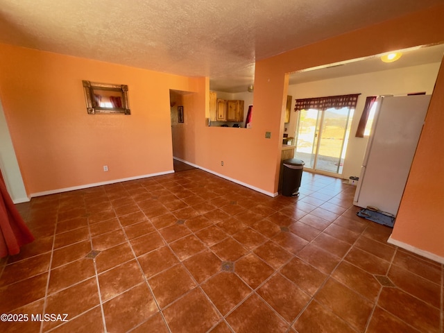 unfurnished room featuring baseboards, dark tile patterned floors, and a textured ceiling