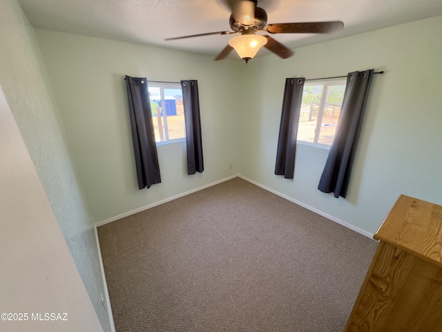 carpeted spare room with a ceiling fan and baseboards