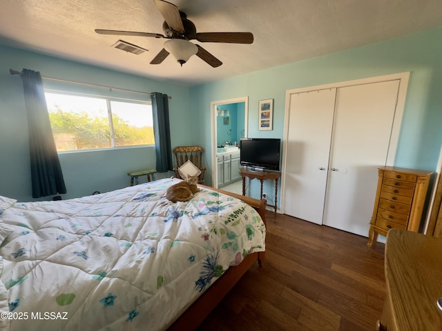 bedroom featuring a closet, ceiling fan, visible vents, wood finished floors, and ensuite bathroom