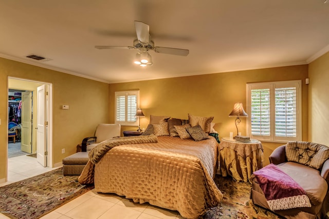 bedroom with tile patterned flooring, crown molding, visible vents, ceiling fan, and a spacious closet