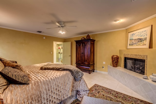 bedroom with visible vents, a tiled fireplace, light tile patterned floors, baseboards, and ornamental molding