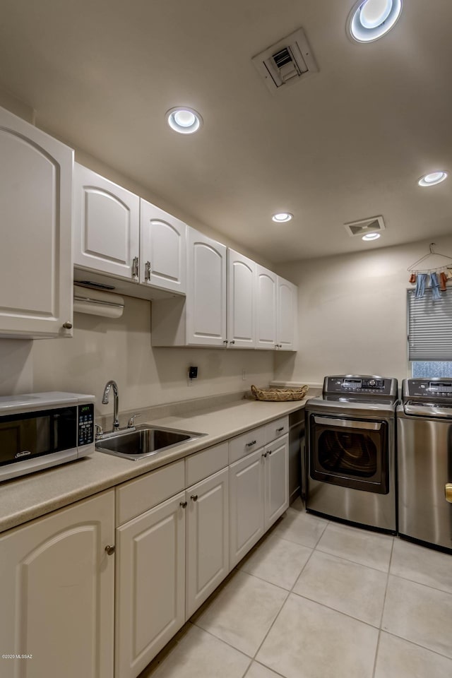 laundry room with laundry area, visible vents, washer and clothes dryer, a sink, and light tile patterned floors
