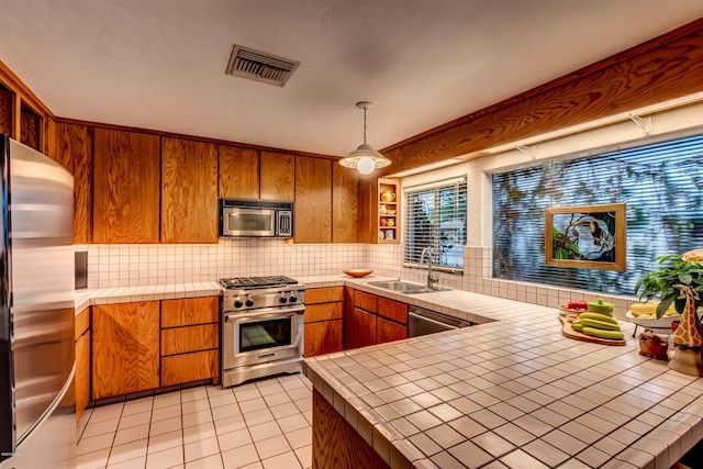 kitchen with visible vents, appliances with stainless steel finishes, tasteful backsplash, a sink, and tile counters