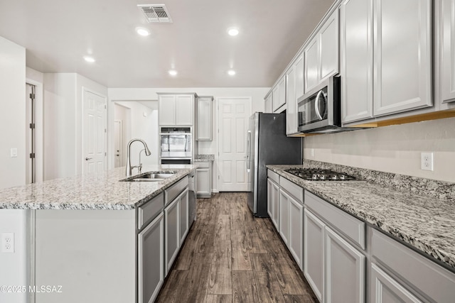kitchen with visible vents, an island with sink, dark wood-style floors, a sink, and appliances with stainless steel finishes