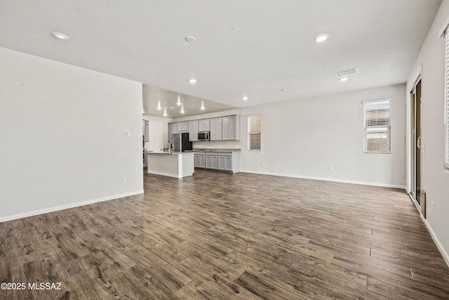 unfurnished living room with recessed lighting, baseboards, and dark wood-style floors