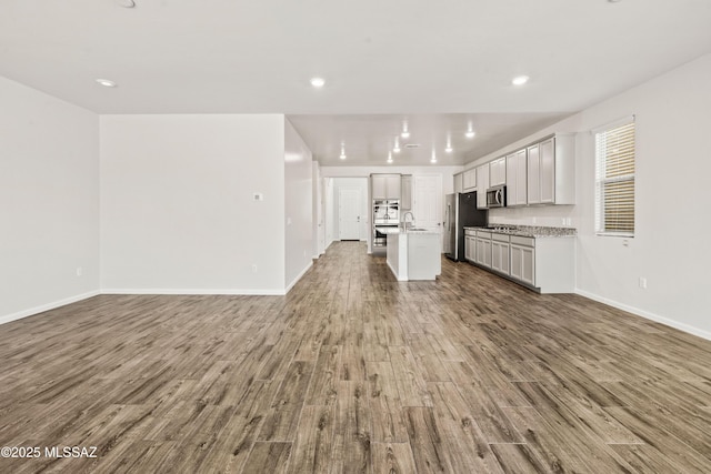 unfurnished living room featuring baseboards, recessed lighting, and wood finished floors