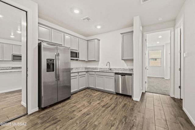 kitchen featuring visible vents, a sink, dark wood finished floors, gray cabinetry, and stainless steel appliances