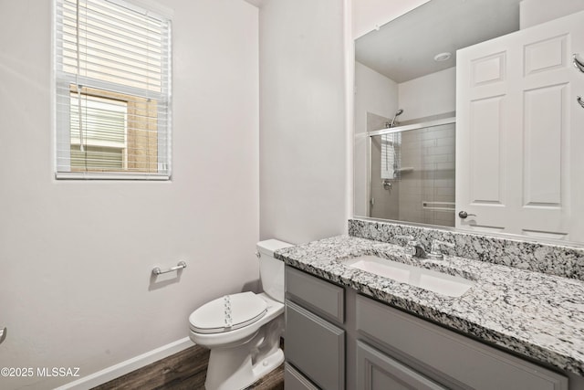full bathroom featuring vanity, toilet, baseboards, wood finished floors, and a stall shower
