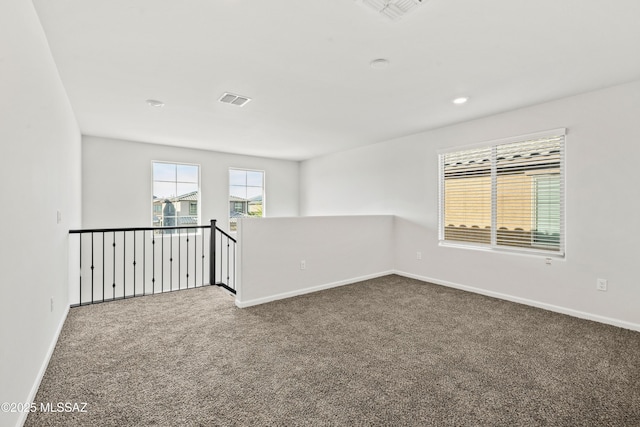 empty room featuring carpet floors, baseboards, and visible vents