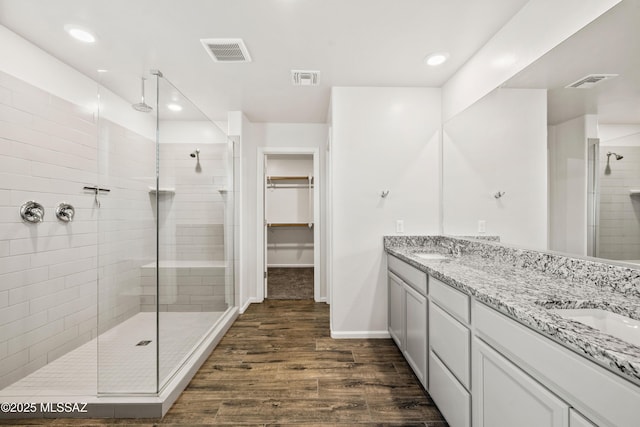 full bath featuring a shower stall, wood finished floors, and visible vents