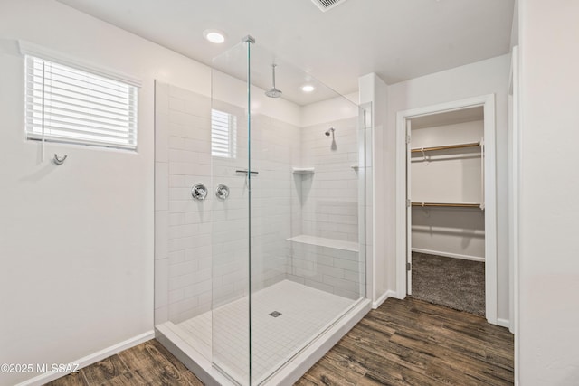 full bathroom featuring a walk in closet, a shower stall, wood finished floors, baseboards, and recessed lighting