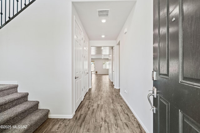 corridor featuring stairs, baseboards, visible vents, and wood finished floors