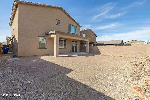 rear view of house with fence, a patio area, and stucco siding