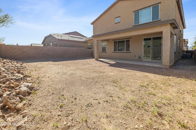 back of house with a fenced backyard, central air condition unit, stucco siding, and a patio area