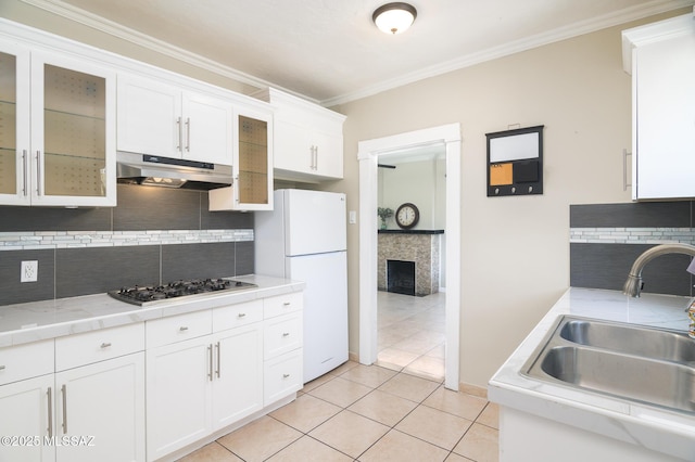 1025 N Perry Ave, Tucson, AZ 85705 - kitchen featuring a sink, under cabinet range hood, light tile patterned floors, white cabinetry, and freestanding refrigerator