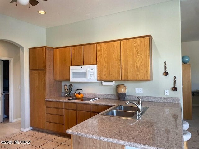 1040 W Stargazer Pl, Oro Valley, AZ 85737 - kitchen featuring white microwave, brown cabinets, a sink, a peninsula, and light tile patterned floors