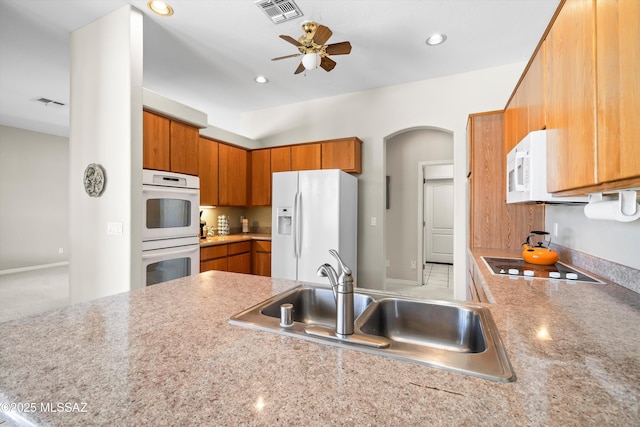 1040 W Stargazer Pl, Oro Valley, AZ 85737 - kitchen with white appliances, a sink, arched walkways, ceiling fan, and brown cabinetry