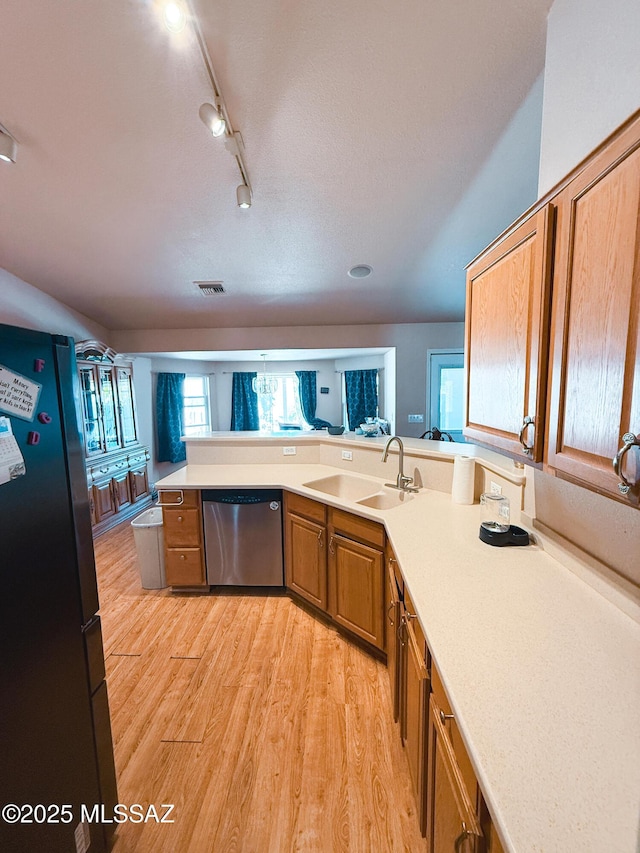 2692 W Dove Ln, Thatcher, AZ 85552 - kitchen featuring appliances with stainless steel finishes, a sink, brown cabinetry, light wood-style floors, and light countertops