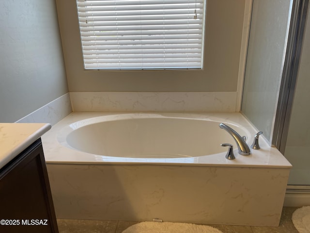 bathroom with a wealth of natural light, a bath, and vanity