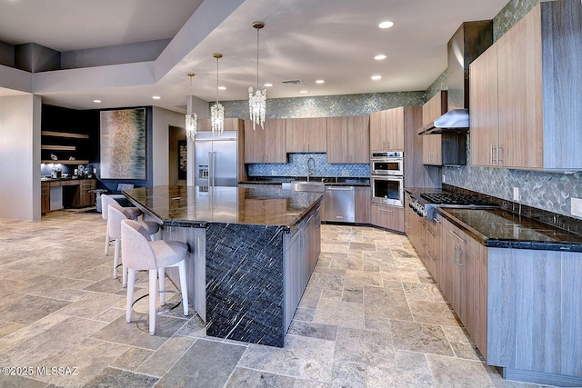 kitchen featuring dark stone countertops, tasteful backsplash, appliances with stainless steel finishes, a large island, and a kitchen breakfast bar