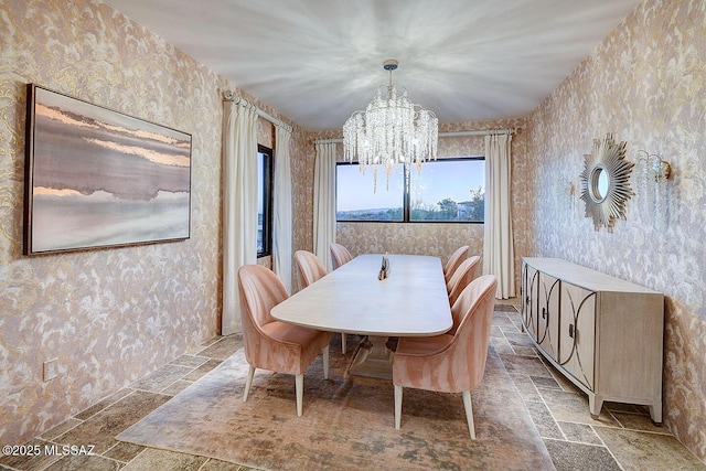 dining area with an inviting chandelier, wallpapered walls, and stone tile flooring