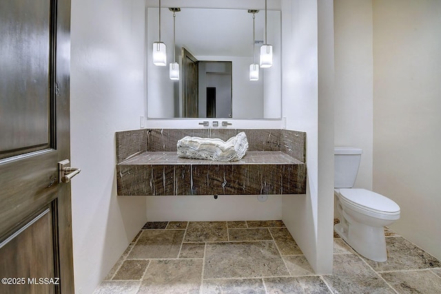 bathroom with stone tile floors and toilet
