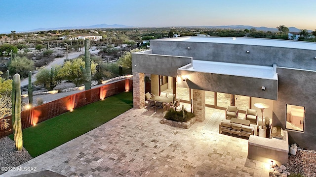 rear view of property featuring stucco siding, a patio area, a mountain view, and a fenced backyard