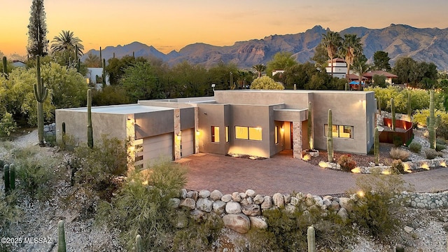 rear view of property featuring a mountain view, a garage, and stucco siding