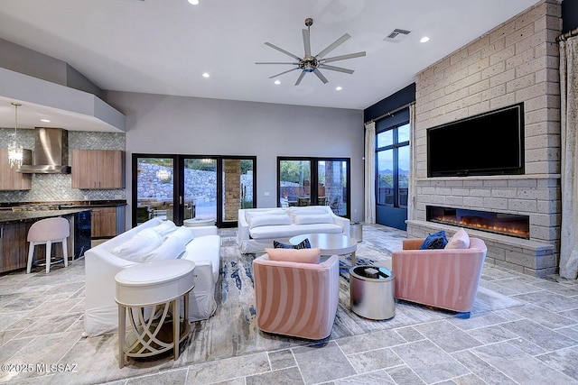 living area with visible vents, ceiling fan, stone tile flooring, recessed lighting, and a fireplace