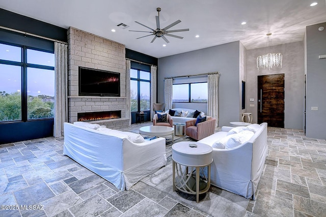 living area featuring stone tile floors, recessed lighting, visible vents, and ceiling fan with notable chandelier